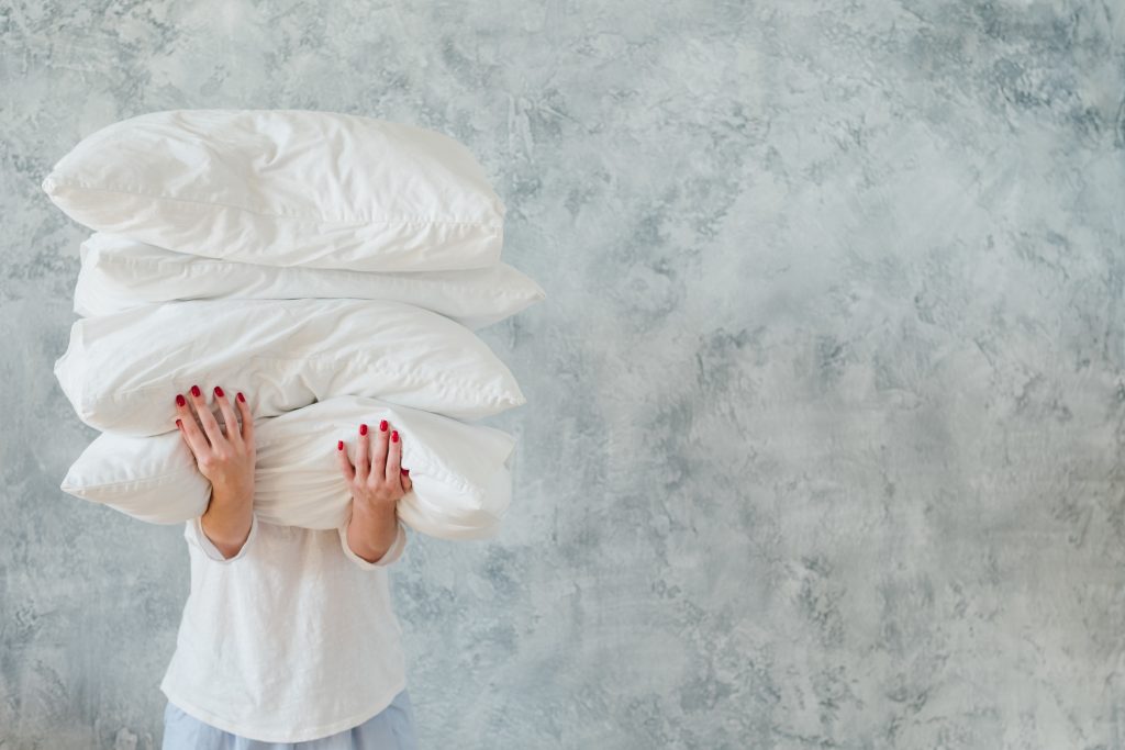 Persoon houdt stapel beste hoofdkussens vast