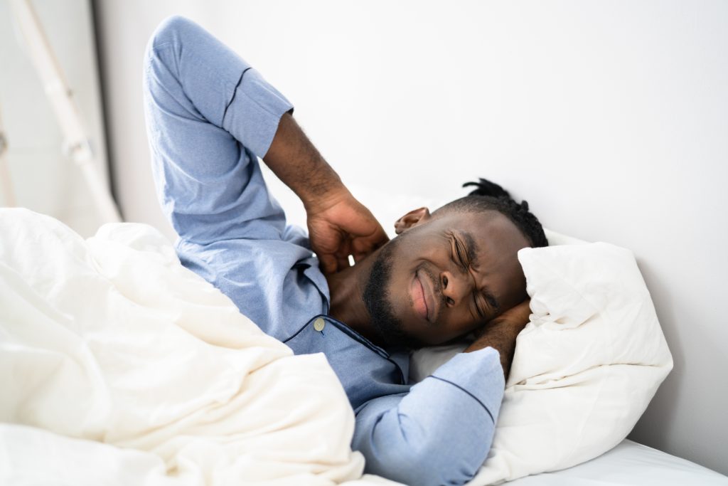 man wordt wakker in bed met nekpijn