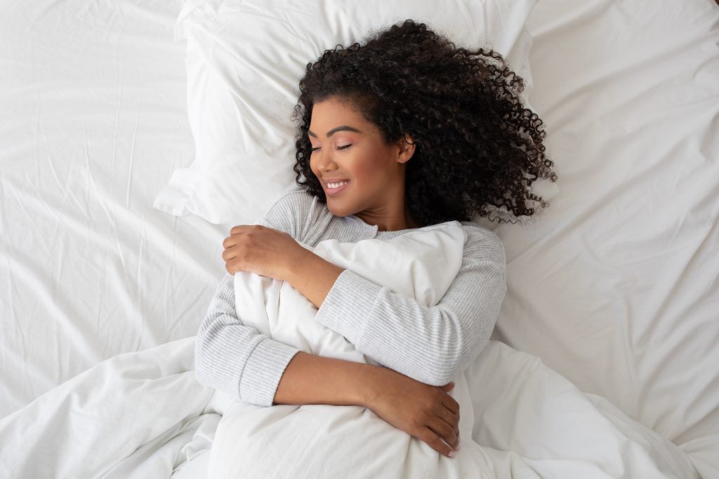 vrouw omhelst lachend verkoelend dekbed