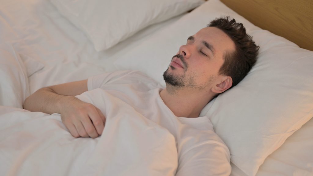 Man is sleeping on his back on a pillow