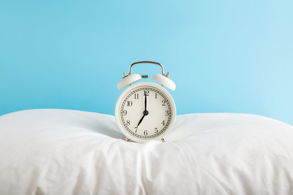 White alarm clock on pillow. Time to replace your pillow.