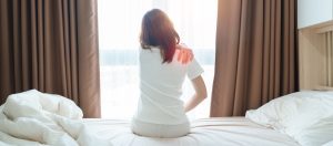 Woman having shoulder pain sitting on bed