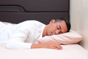 Asian man sleeping on his stomach on a pillow